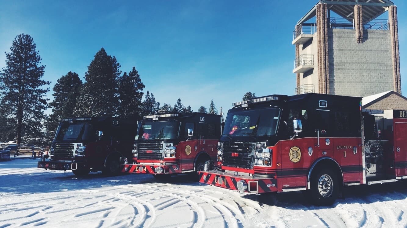 Three Bend Fire engines parked in the snow beside the training tower